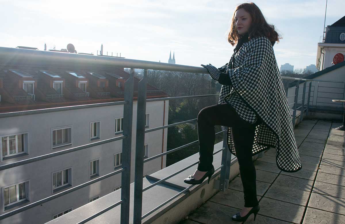 poncho-outfit-mit-hahnentrittmuster-stehend-mit-einem-fuss