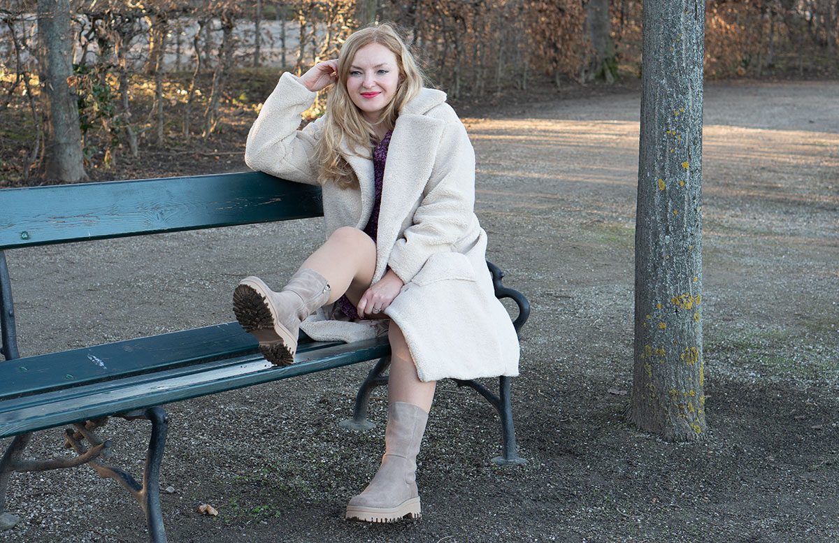 Winter-Trend-2022-Teddy-Mantel-und-Chelsea-Boots-auf-parkbank